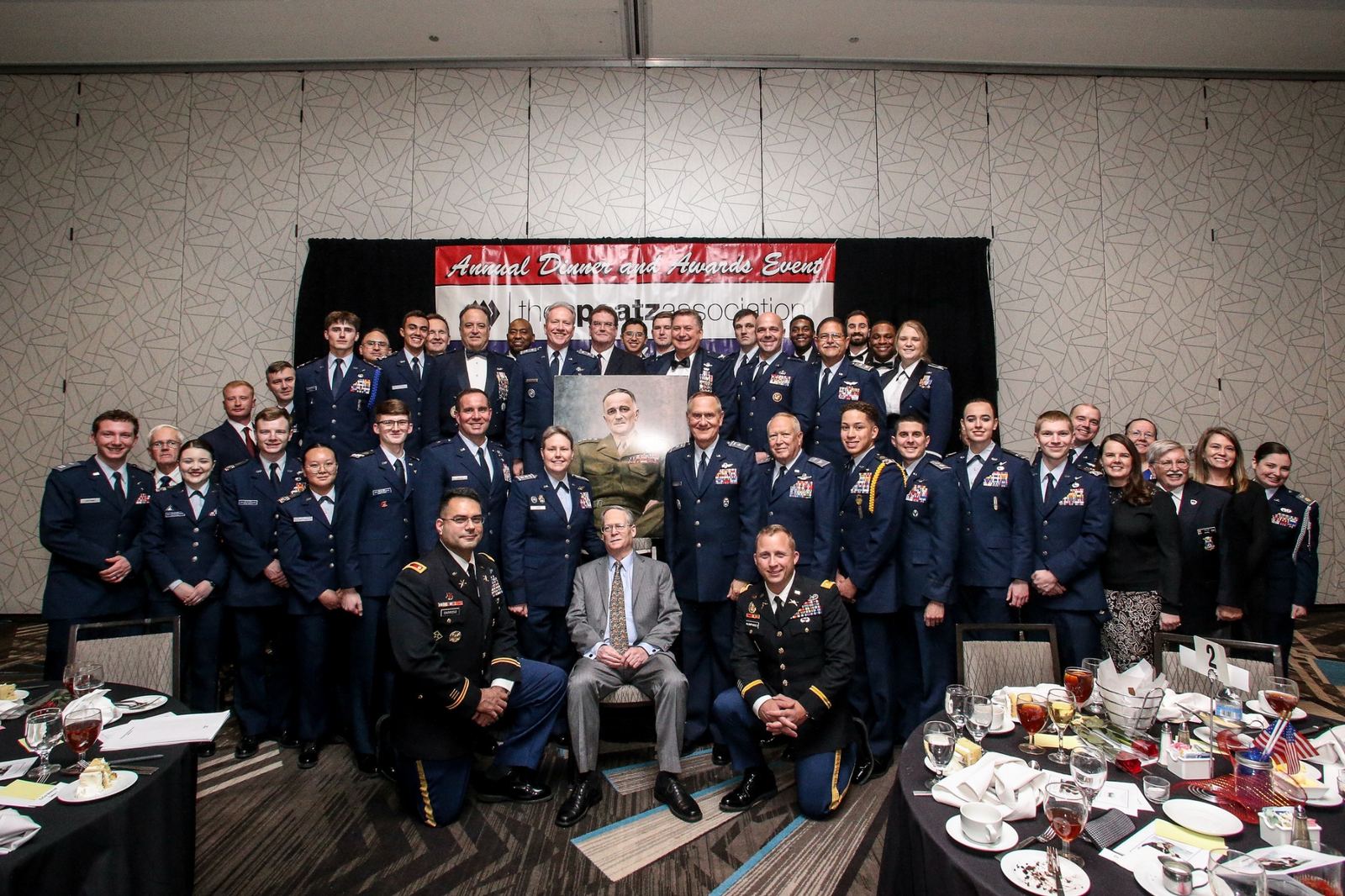 Spaatz Award recipients, cadets and guests in dress uniform gather around a portrait of General Spaatz at the Annual Dinner and Awards Event.